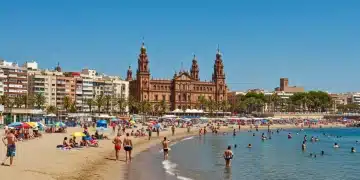 Playa española vibrante con turistas y arquitectura icónica, simbolizando el atractivo de España en el turismo global.
