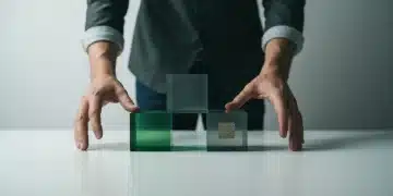 A person's hands interlocking translucent green and grey geometric blocks on a white surface, symbolizing the interconnected structure of government benefits and social safety nets.