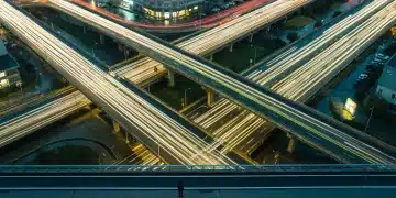 Aerial view of a complex urban road network at dusk, with streams of green and yellow car lights forming intricate geometric patterns, symbolizing evolving career paths.